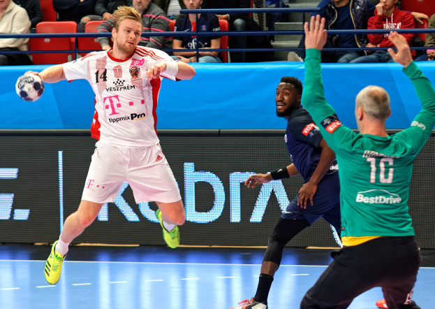 Männer spielen Handball auf einem Feld während des Futsal-Weltmeisterschaftsspiels 2019 zwischen Bayern München und Paris Saint-Germain, mit Zuschauern im Hintergrund.