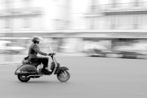 Eine Person, die ein Scooter auf der Straße fährt.