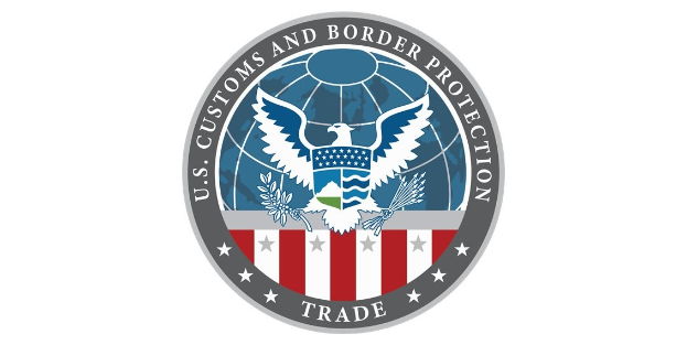 Logo des U.S. Customs and Border Protection Trade mit einem blauen Kreis mit einem weißen Stern, einer weißen Taube mit ausgebreiteten Flügeln darin und dem Text "U.S." darüber, alles auf einem weißen Rand.