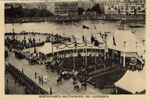 Schwarzes und weißes Foto einer Menschenmenge bei einem Karneval mit Zelten, Fahnen, Mästängen, Pferden, Gebäuden, Bäumen und Wasser im Hintergrund, mit Text unten.