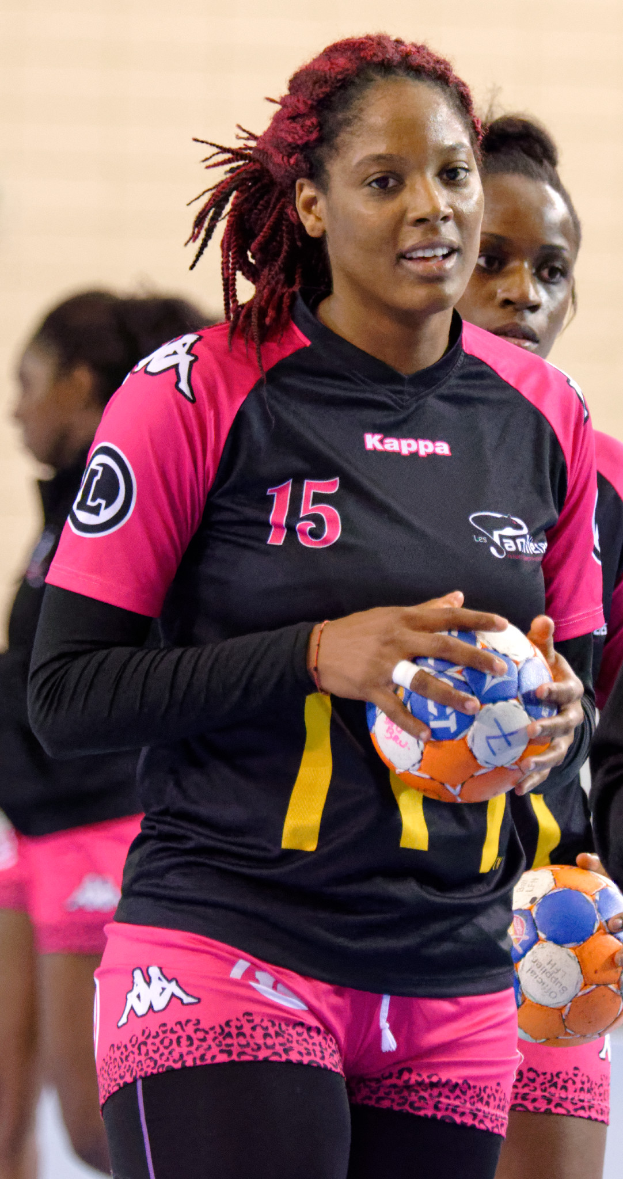 Eine Gruppe von Frauen, die nebeneinander stehen und jeweils einen Fußball halten, wobei die Frau in der Mitte ein menschliches Gesicht hat und direkt in die Kamera schaut, trägt ein weißes T-Shirt und blaue Shorts.