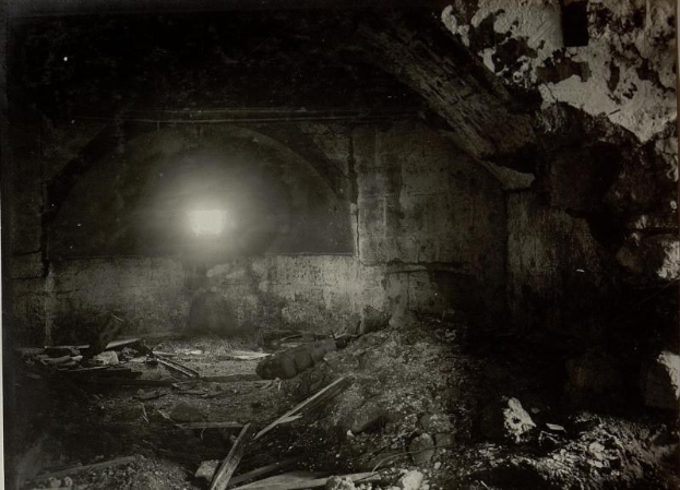 Schwarz-weiß-Foto eines zerfallenden Tunnels in den Berliner Mauertrümmern, mit Schutt auf dem Boden und einem Licht am Ende.