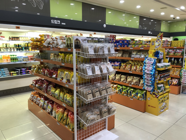 Ein hell erleuchteter Supermarktgang mit verschiedenen Lebensmitteln in Packungen, Flaschen und Regalen.