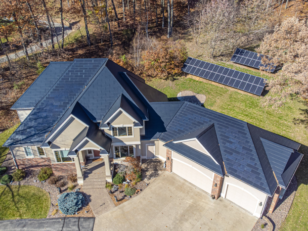 Luftaufnahme eines Hauses in North Carolina mit Solarpaneelen auf dem Dach, umgeben von grünem Gras, Pflanzen und Bäumen.