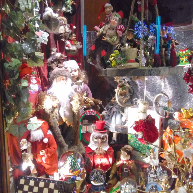Ein Schaufenster voller Weihnachtsdekorationen, darunter Puppen, Spielzeug und andere festliche Gegenstände.