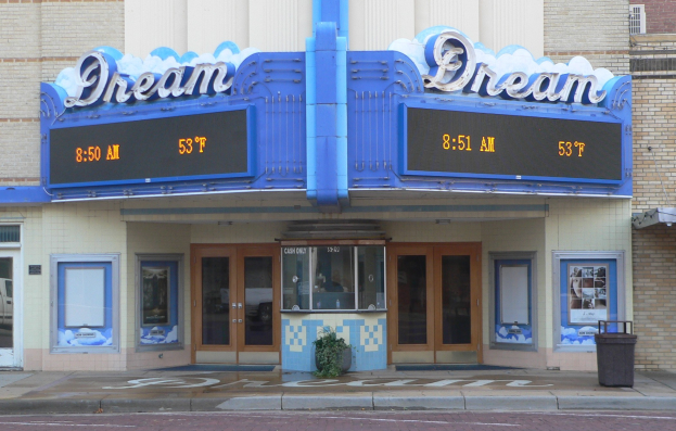Außenansicht des Dream Theaters in St. Louis, Missouri, mit Glastüren und -fenstern, einem Namen-Schild, einem Mülleimer, einem Topf-Pflanze und einer Straße unten.