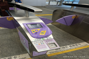 Gruppe von Menschen vor einem Metalldetektor an einem Bahnhof, mit einem weiteren Metalldetektor rechts und zusätzlichen Menschen im Hintergrund