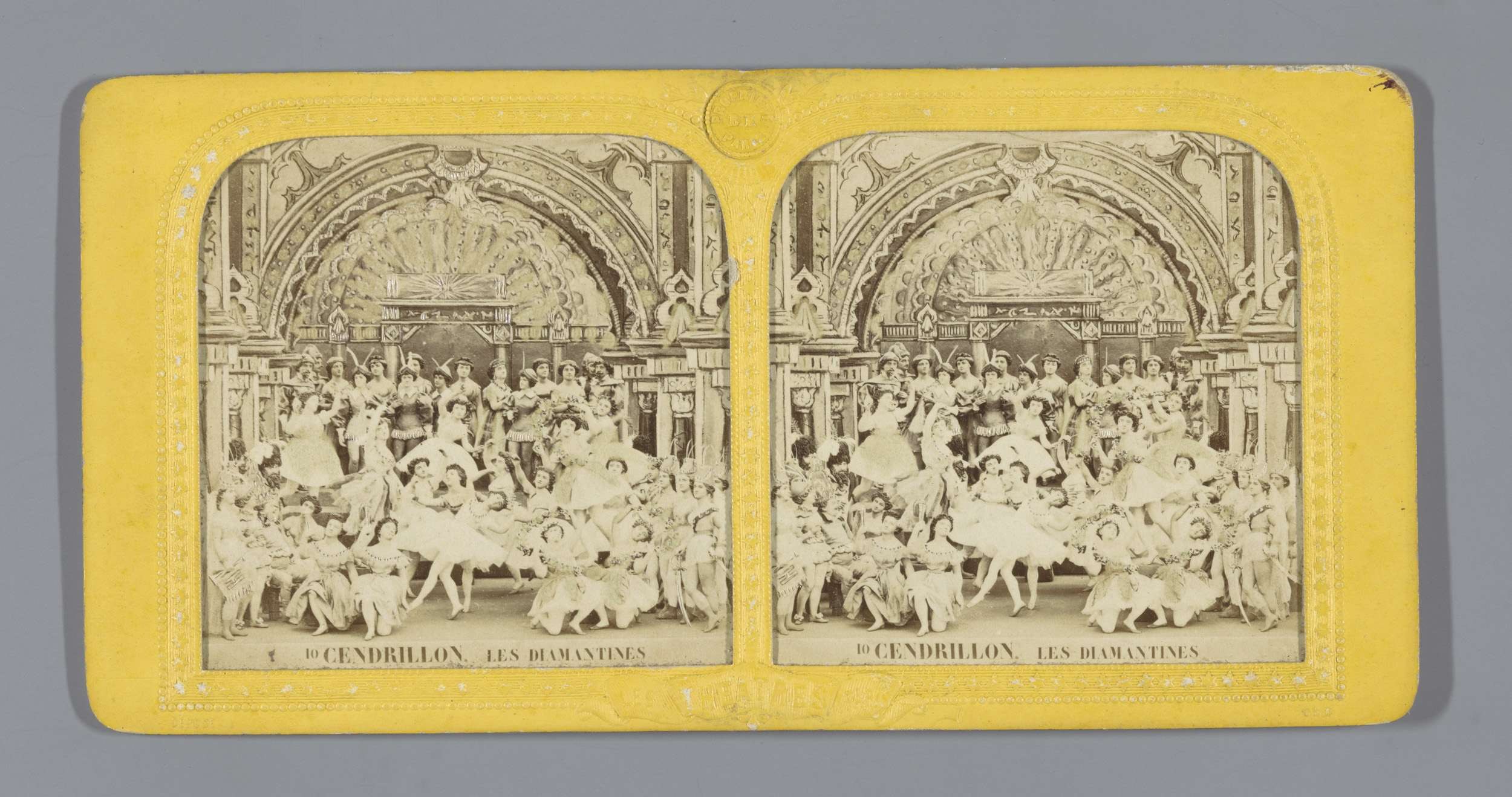 Schwarz-weiß-Foto von Menschen in bunten Kostümen, die vor einem Gebäude mit aufwändigen Verzierungen tanzen.