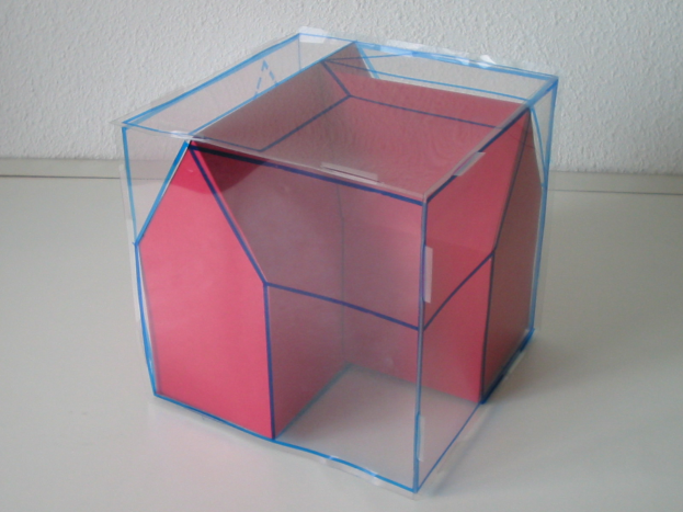 Ein pinker und blauer Wahlkasten mit offenem Deckel auf einem weißen Tisch stehend, an einer Wand lehnend.