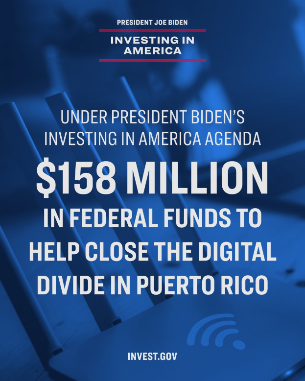Plakat mit der Aufschrift "Unter Präsident Bidens America Agenda: 158 Millionen Bundesmittel, um die digitale Kluft in Puerto Rico zu schließen" mit einem Laptop, Papieren und einem Kaffeebecher auf einem Tisch davor.