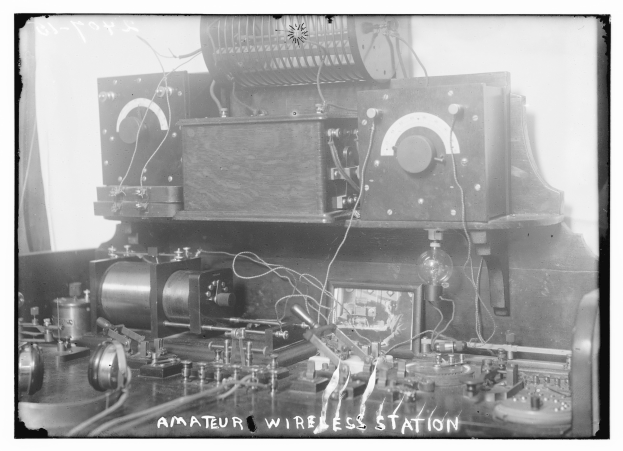 Schwarz-weiß-Foto einer Amateur-Funkstation mit elektronischen Geräten und Drähten, mit Text unten.