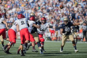 Eine Gruppe von Menschen in Helmen und Schuhen, die Fußball auf einem Feld spielen, mit einem Ball in der Luft und einem unscharfen Hintergrund.