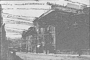 Schwarz-weiß-Foto eines Gebäudes mit Stacheldraht oben auf einer Straße mit einem Himmel-Hintergrund, beschriftet mit "New York Post Office, New York City" unten.