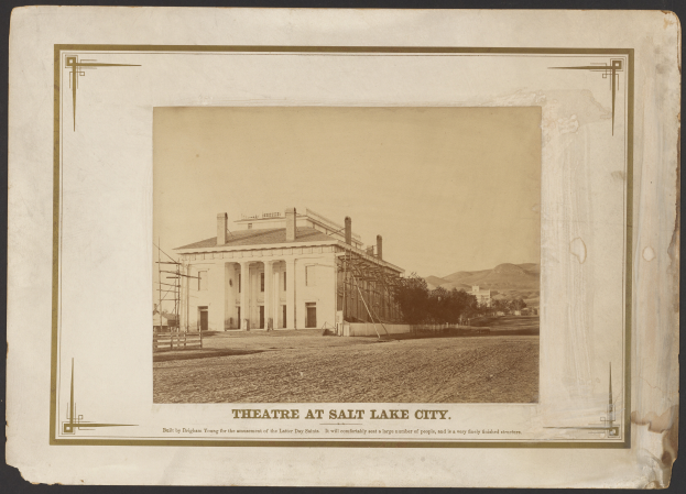 Ein Schwarz-Weiß-Foto des Theaters in Salt Lake City, mit einem zentralen Gebäude umgeben von Bäumen und Hügeln und Text unten.