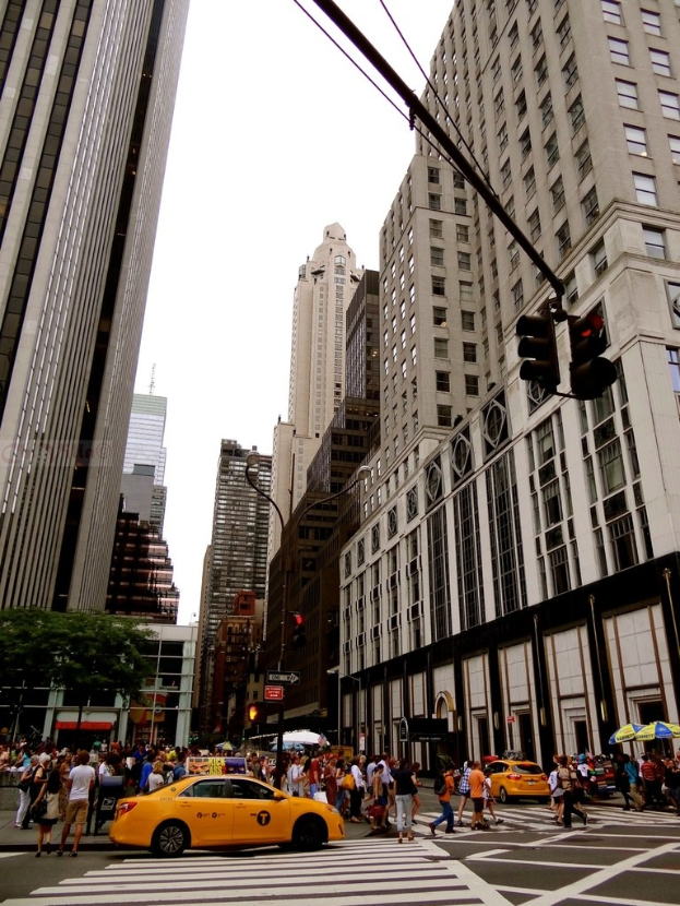 Gebäude, Verkehrszeichen, Fenster, Menschen, Autos und Himmel in einer städtischen Umgebung.