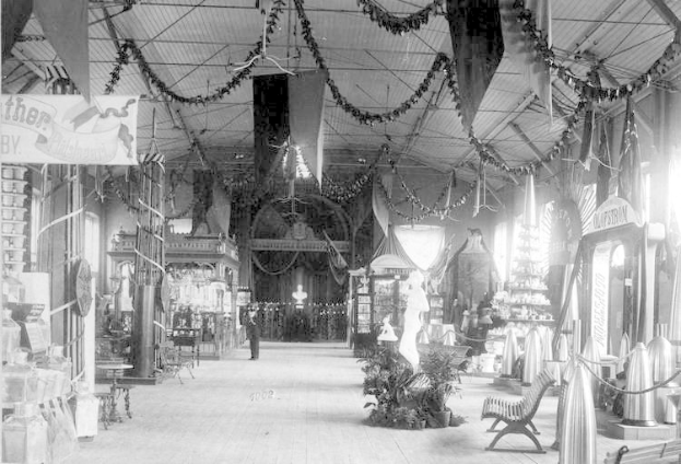 Schwarzes und weißes Foto eines Geschäftsinneren, das mit Weihnachtsartikeln wie Schaufensterpuppen, Stühlen, Pflanzen, Pfosten, Lichtern und Bannern dekoriert ist.