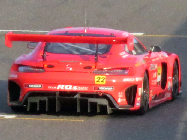 Ein leuchtend roter Porsche 911 GTS Rennauto mit großer Heckspoiler und Flügel, der auf einer Rennstrecke fährt.