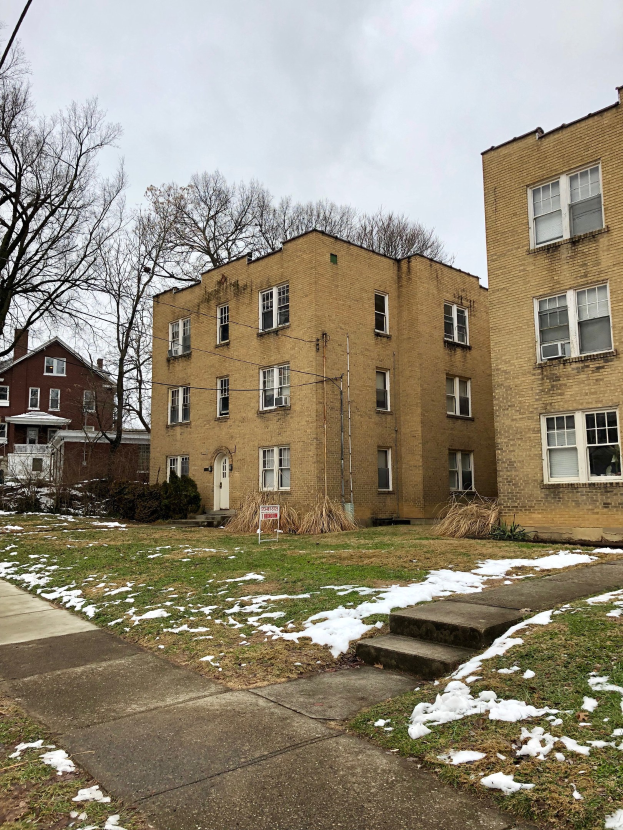 Wohngebäude mit schneebedecktem Boden, einem Weg, Bäumen, Pflanzen, einem Schild mit der Aufschrift "Mietwohnungen zu vermieten, listingid 29058910, Lage 5901 North Elmwood Avenue Chicago 60618", Drähten und einem bewölkten Himmel.
