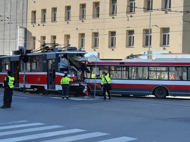 Rote und weiße Straßenbahn krachte auf der Seite der Straße mit einigen Menschen in der Nähe und einem Gebäude im Hintergrund.