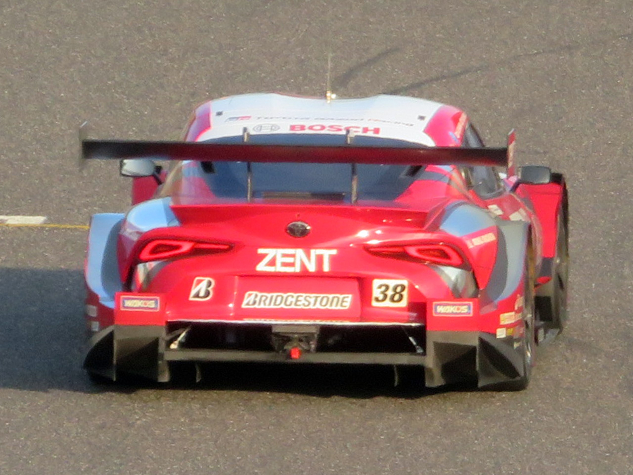 Ein rotes Sportauto mit Text und Zahlen nimmt an den 24 Stunden von Le Mans teil und fährt auf einer Rennstrecke.