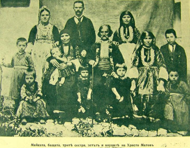 Schwarz-weißes Foto einer Familie, die vor einer Vorhangwand posiert, beschriftet mit "Russische Familie in den frühen 1900er Jahren".